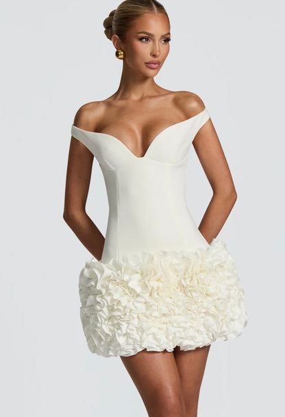 Mini Dress LIVIA 
Un mini dress raffinato e sofisticato, con scollo a cuore off-shoulder che valorizza il décolleté e una gonna arricchita da dettagli floreali tridimensionali. Perfetto per party, eventi esclusivi o come abito da cocktail