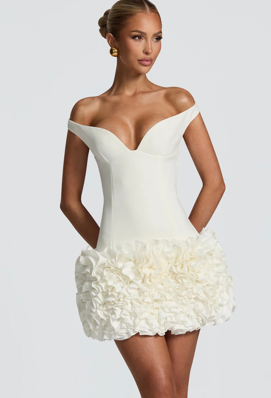 Mini Dress LIVIA 
Un mini dress raffinato e sofisticato, con scollo a cuore off-shoulder che valorizza il décolleté e una gonna arricchita da dettagli floreali tridimensionali. Perfetto per party, eventi esclusivi o come abito da cocktail
