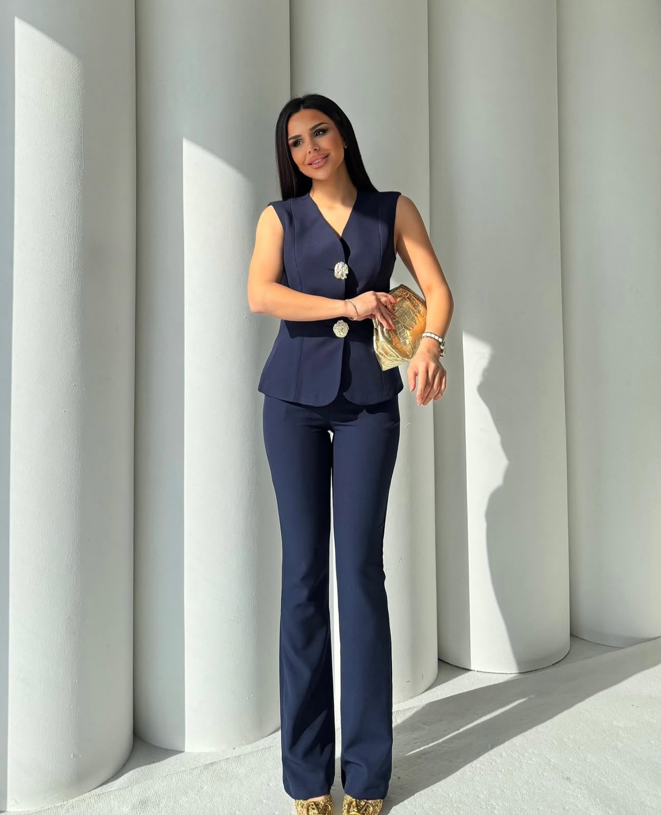 Set cord PERLA elegante composto da un gilet smanicato e un paio di pantaloni a gamba larga  Il gilet presenta due bottoni decorativi centrali dal design gioiello. I pantaloni sono a vita alta, con una vestibilità morbida e fluida