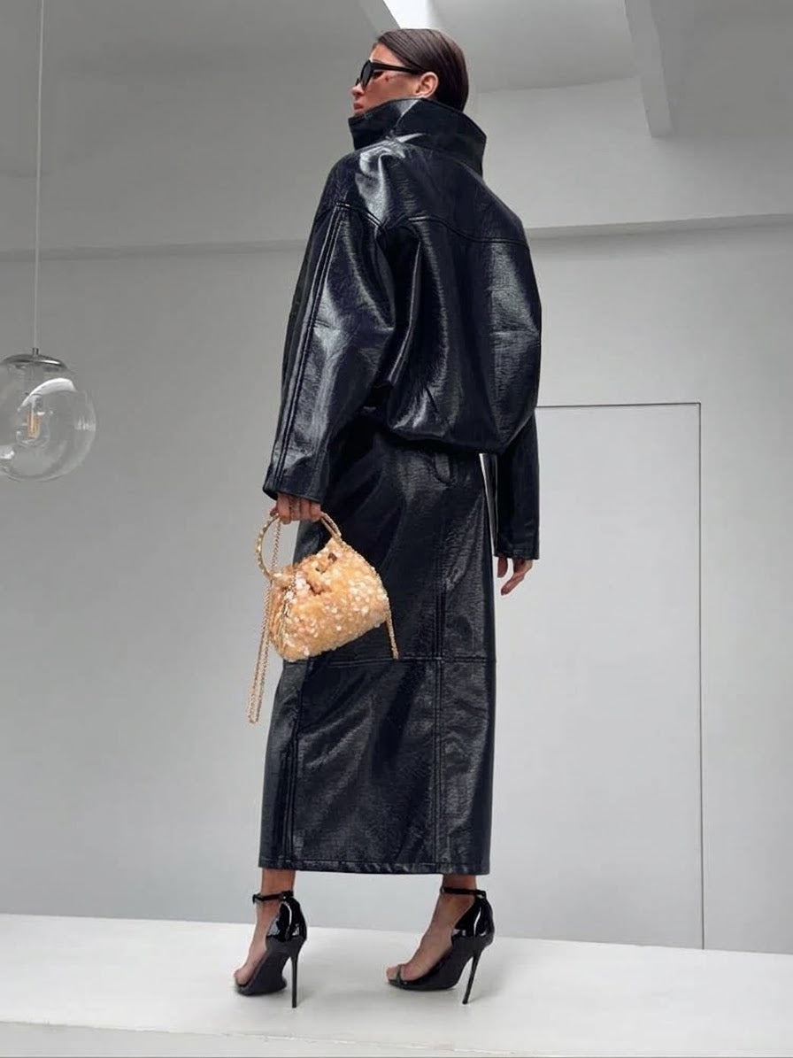 Co-ord Set in Similpelle Lucida Effect Noir
L'audacia incontra l'eleganza contemporanea. Eleva il tuo guardaroba con questo esclusivo coordinato a due pezzi, composto da una giacca bomber dallo stile urban-chic e una gonna midi dalla silhouette affusolata