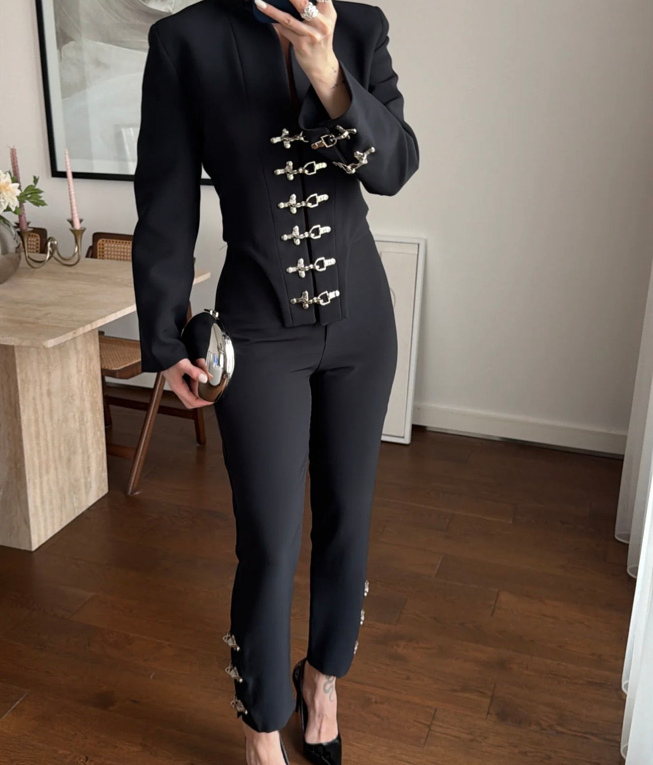 Tailleur Rosella caratterizzato da dettagli in metallo argentato con fibbie decorative sul davanti della giacca e sulla caviglia del pantalone.