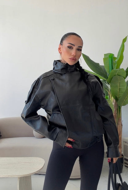 Giacca Biker Oversize in pelle Caratterizzata da una silhouette strutturata con spalle scese e un collo alto avvolgente con cinturino, è il capo spalla perfetto per completare i tuoi outfit streetwear ed eleganti con un tocco audace.