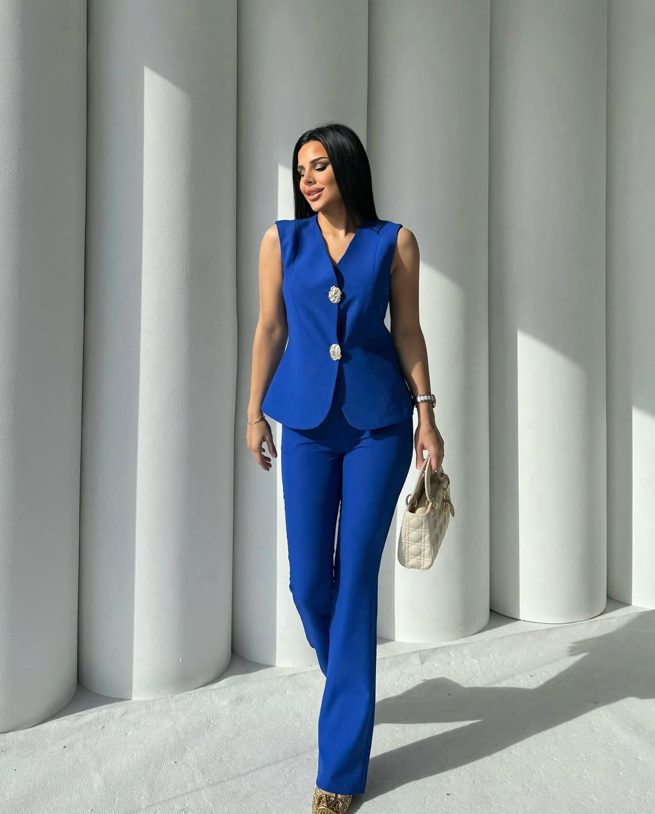 Set cord PERLA elegante composto da un gilet smanicato e un paio di pantaloni a gamba larga  Il gilet presenta due bottoni decorativi centrali dal design gioiello. I pantaloni sono a vita alta, con una vestibilità morbida e fluida