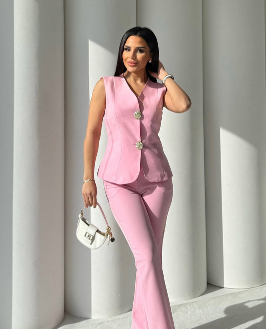 Set cord PERLA elegante composto da un gilet smanicato e un paio di pantaloni a gamba larga  Il gilet presenta due bottoni decorativi centrali dal design gioiello. I pantaloni sono a vita alta, con una vestibilità morbida e fluida