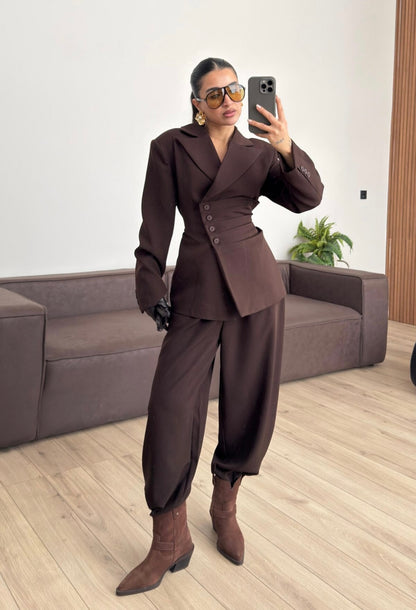 Tailleur Samantha”in promo” composto da giacca sartoriale con spalle strutturate e chiusura incrociata. La cintura integrata con bottoni decorativi stringe il punto vita valorizzando la silhouette e creando un elegante effetto corsetto l pantalone fluido