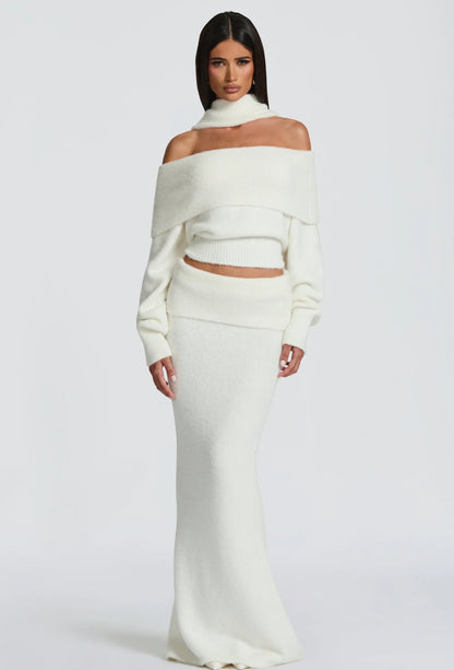 Set BIANCA composto da maglia off-shoulder e gonna lunga a sirena. Realizzato in morbida maglia calda, avvolge la silhouette con eleganza e comfort. Il design con collo ad anello e spalle scoperte aggiunge un tocco sofisticato e sensuale