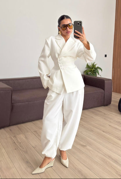 Tailleur Samantha”in promo” composto da giacca sartoriale con spalle strutturate e chiusura incrociata. La cintura integrata con bottoni decorativi stringe il punto vita valorizzando la silhouette e creando un elegante effetto corsetto l pantalone fluido