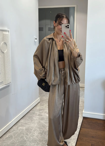 Coordinato PRISCILLA Completo elegante e versatile in tessuto satinato composto da giacca leggera oversize con zip e pantaloni ampi a vita alta con coulisse. Perfetto per look chic e confortevoli, dal giorno alla sera.