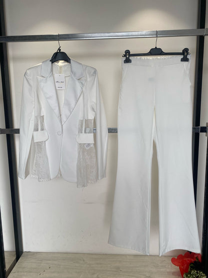 Tailleur MIA elegante composto da blazer e pantaloni coordinati, disponibile in quattro colori raffinati: nero, beige, rosa e azzurro. Il blazer presenta un elegante rever in raso e dettagli in pizzo trasparente sui lati pantalone classico