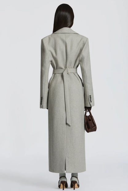 Cappotto ANGELICA lungo grigio in lana, con bottoni frontali e maxi revers a scialle. La linea dritta e sartoriale slancia la figura, mentre il colletto ampio aggiunge un tocco sofisticato. Perfetto per look invernali raffinati, dal giorno alla sera.