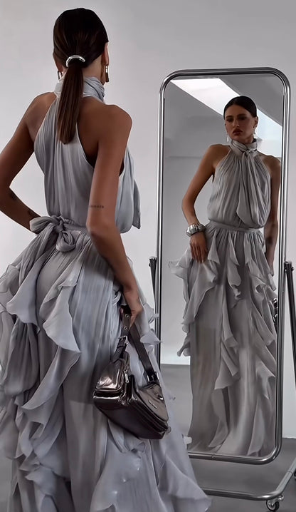 Abito Rouches maxi dress con scollo all'americana, collo con fiocco e gonna a cascata di rouches multistrato pensato per chi vuole essere al centro della scena senza sforzo. La silhouette fluida e il tessuto leggero lo rendono perfetto