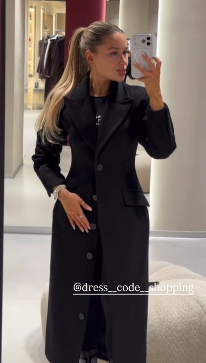 Cappotto ANGELICA lungo grigio in lana, con bottoni frontali e maxi revers a scialle. La linea dritta e sartoriale slancia la figura, mentre il colletto ampio aggiunge un tocco sofisticato. Perfetto per look invernali raffinati, dal giorno alla sera.