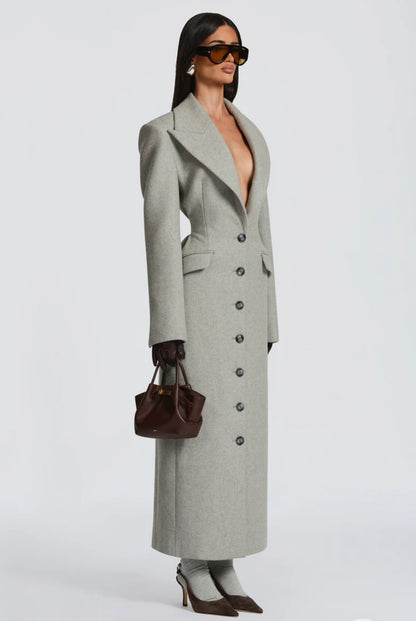 Cappotto ANGELICA lungo grigio in lana, con bottoni frontali e maxi revers a scialle. La linea dritta e sartoriale slancia la figura, mentre il colletto ampio aggiunge un tocco sofisticato. Perfetto per look invernali raffinati, dal giorno alla sera.