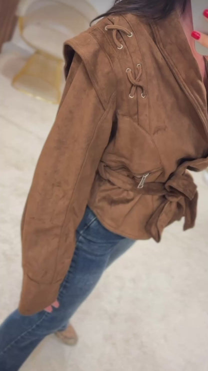 Giacca FIAMMA Giacca dal taglio moderno in morbido suede marrone, caratterizzata da dettagli con lacci sulle spalle e zip laterali. La cintura in vita sottolinea la silhouette, rendendola un capo versatile